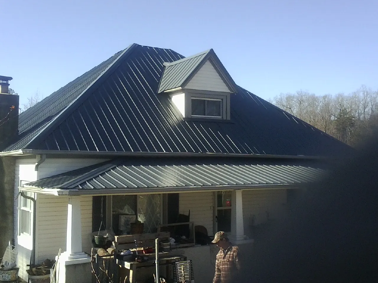 Dark blue standing seam metal roof with a dormer above a front porch in Moorhead