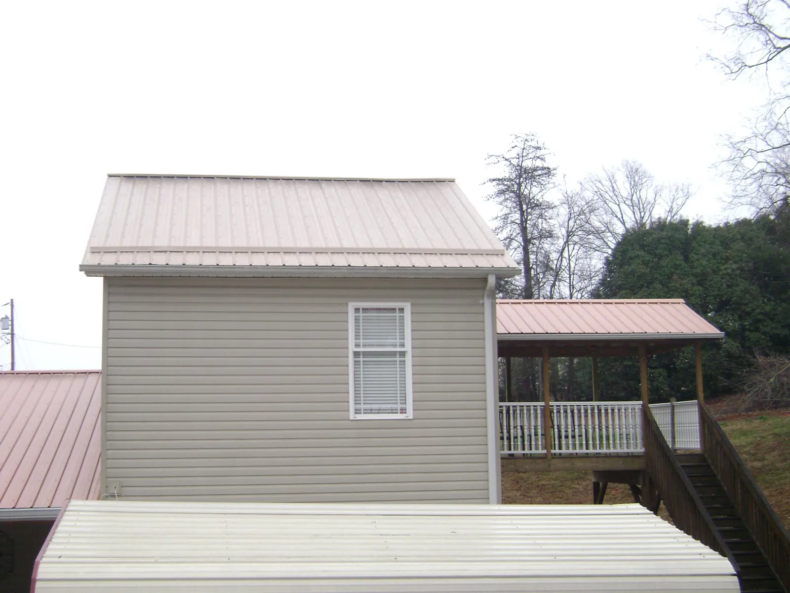 Tan metal roofs on a two story addition and attached porch, from a Roof Replacement job in Moorhead